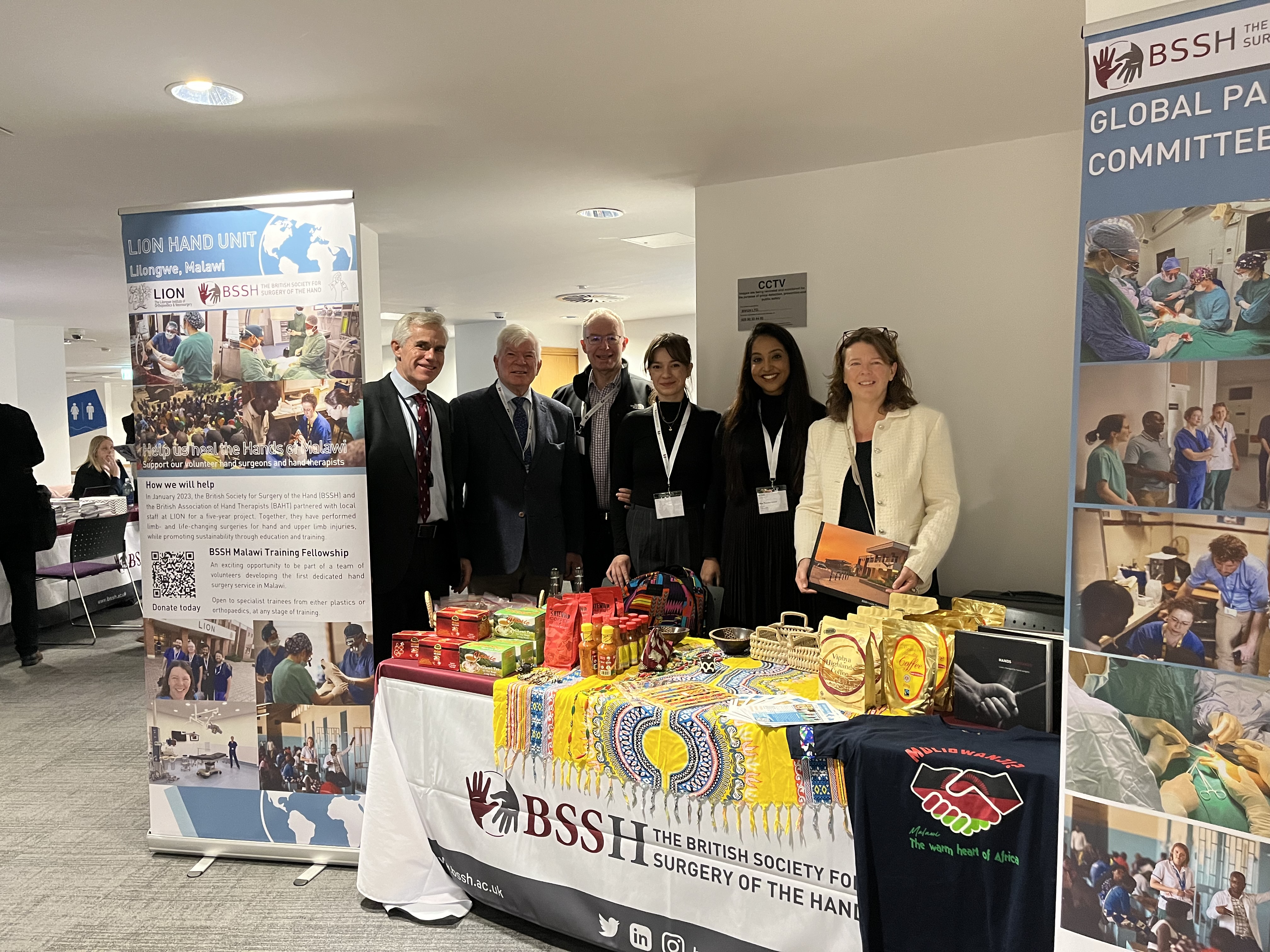 A group of people standing in front of a table with a displayDescription automatically generated